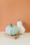 Small cream and teal pumpkin on orange background.