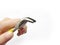 Small crooked pliers with bright yellow handles are squeezed in the left hand an  object on a white background