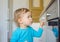 Small and curious child playing with the knobs of the oven in the kitchen. Danger for unattended children, accident prevention at