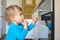 Small and curious child playing with the knobs of the oven in the kitchen. Danger for unattended children, accident prevention at