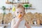 A small curly blonde girl poses in the kitchen during breakfast, eating a croissant, cakes, cookies