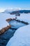 Small curved creek winds through snowy field with mountain Grimming