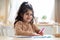 Small Cute Arab Girl Drawing Picture While Sitting At Table In Kitchen