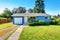 Small cute blue house with driveway and trimmed hedges.