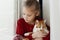 A small cute child gently embraces a red fluffy cat