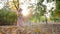 Small cute girl plays with soap bubbles in backlight at autumn park