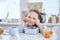 Small cute girl sitting at the table and having tasty lunch