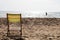 Small deck chair on the sand of a beach with the sea