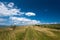 Small dirt road leading on the top of a hill , beautiful blue sky with white clouds