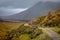 Small dirt road winds from lower right to center with train tracks visible across fence in Glencoe, Highland, Scotland, UK