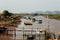 Small dirty river with boats and bridges in Asia