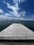 Small dock jutting out into a tranquil lake beneath a cloudy sky