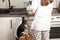 A small dog at home asks for food from the hostess while she cooks in the kitchen