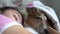 Small dog opens eyes lying in teenage girl hugs on bed