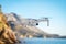 Small drone flies on a background of landscape of mountains, sea and blue sky