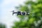 Small drone in flight against defocused foliage