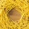 Small dry frame pasta noodles on wood background