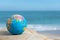 Small earth globe lies on a rock on a tropical beach.