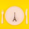 Small Eiffel tower love symbol plate serving plastic tableware copy space on bold yellow background in creative minimal style.