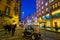 The small electric vehicle drives along wide night illuminated Via Torino street, Milan, Italy