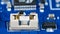 Small electrical fuse in white holder and black linear fixed voltage regulator on blue PCB