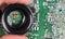 Small electronic components in black loupe on green PCB background