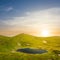 Small emerald lake in a green mountain bowl at the sunset