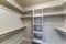 Small empty walk-in closet with shelves and metal rods