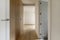 Small entrance hallway to a modern designed bedroom with custom-made built-in wardrobe with light oak wooden doors and matching