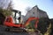 Small excavator on a consruction site hill in front of an ancient castle ruin