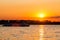 A small excursion riverboat floats on the river against the backdrop of a picturesque sunset