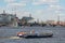 Small excursion ship with tourists sails on the Neva River opposite the legendary cruiser Aurora