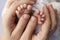 Small feet of a newborn in the hands of parents. Loving palms of the hands of mother. Conceptual image of fatherhood.