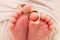 Small feets and fingers of the newborn baby with wedding rings close-up