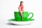 Small female sitting on giant coffee cup; woman on diet,