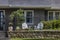 Small fenced garden area outside entrance to stucco house with two adult chairs and one childs chair