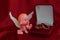 A small figure of an angel sitting near a jewelry box close up on red background