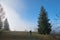 Small figure of lonely hiker enjoying his time on wild forest trail on foggy autumn day