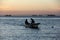 Small fishing boat on background of the sunset sky, silhouettes of fishermen, La Paz, BCS, Mexico