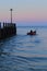 Small fishing boat passing wooden groyne