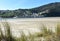 Small fishing village from beach with grass on sand dunes. O Barqueiro or El Barquero, Galicia, Spain.