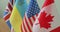 Small flags of different countries on table. Flags of Canada, American, United Kingdom, Ukraineon the desk in focus.