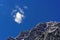 Small fluffy cloud in rich blue sky over mountain peak