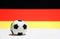 Small football on the white floor with black red and yellow color of German nation flag background.