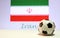 Small football on the white floor and Iranian nation flag with the text of Iran background.