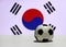 Small football on the white floor with out focus red and blue Yin Yang and four black trigrams of South Korean nation flag.