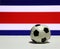 Small football on the white floor with out focus white red and blue color of Costa Rica nation flag background.