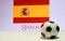 Small football on the white floor and Spanish nation flag with the text of Spain background.