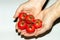 small fresh red tomatoes, female hands, white background.