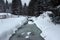 Small frozen river with fresh snow on the rocks